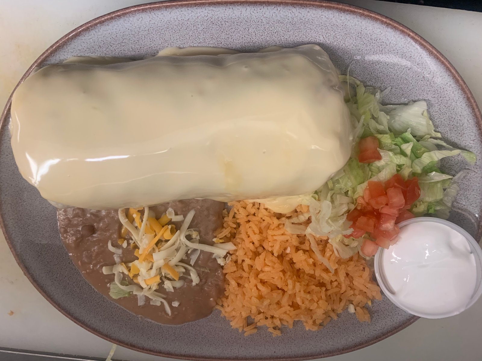Burrito Suizo smothered in cheese sauce with rice and beans